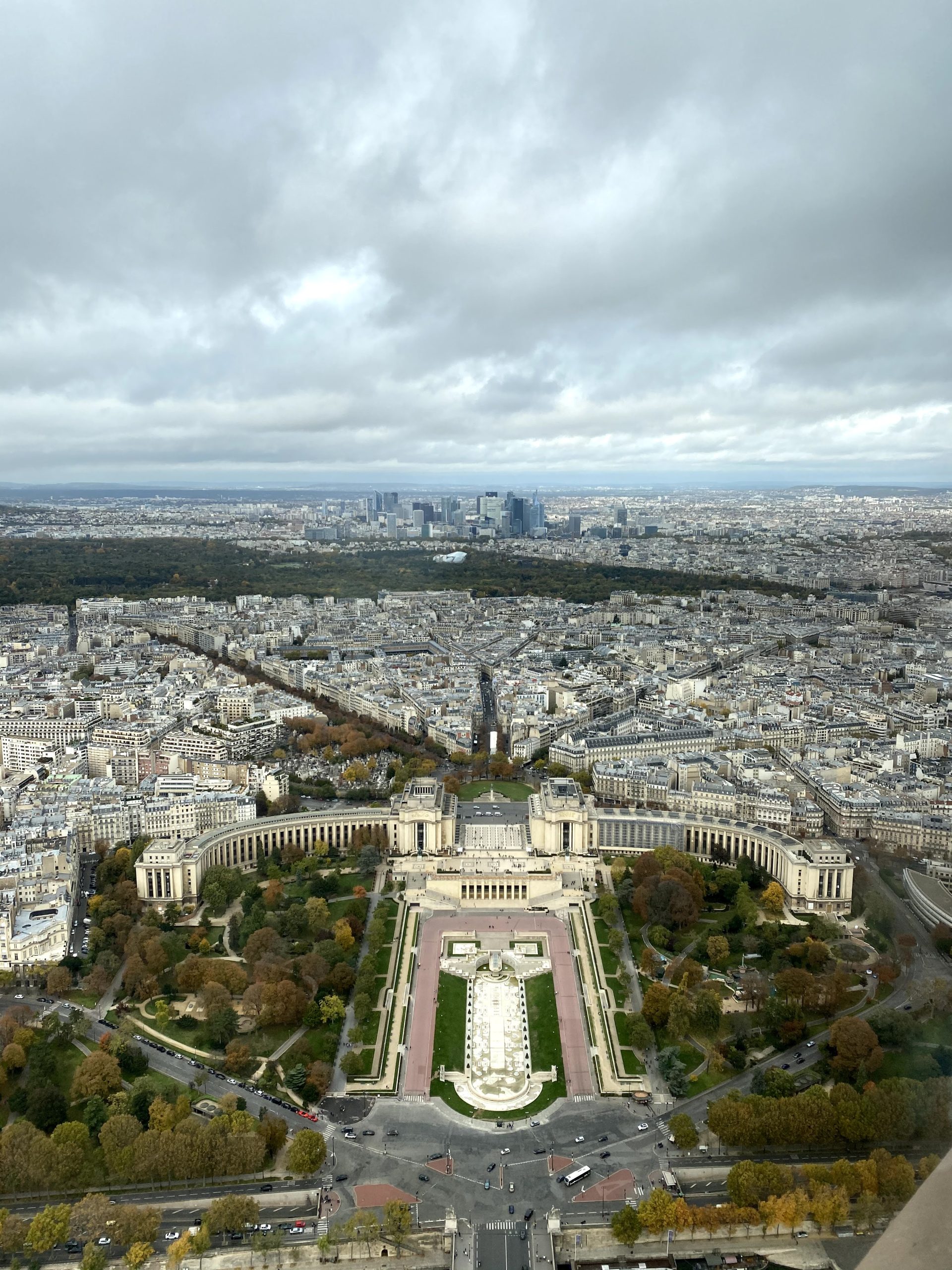 Vue panoramique aérienne depuis le sommet de la tour Eiffel montrant les jardins du Trocadéro, le palais de Chaillot et la silhouette de La Défense à Paris.
